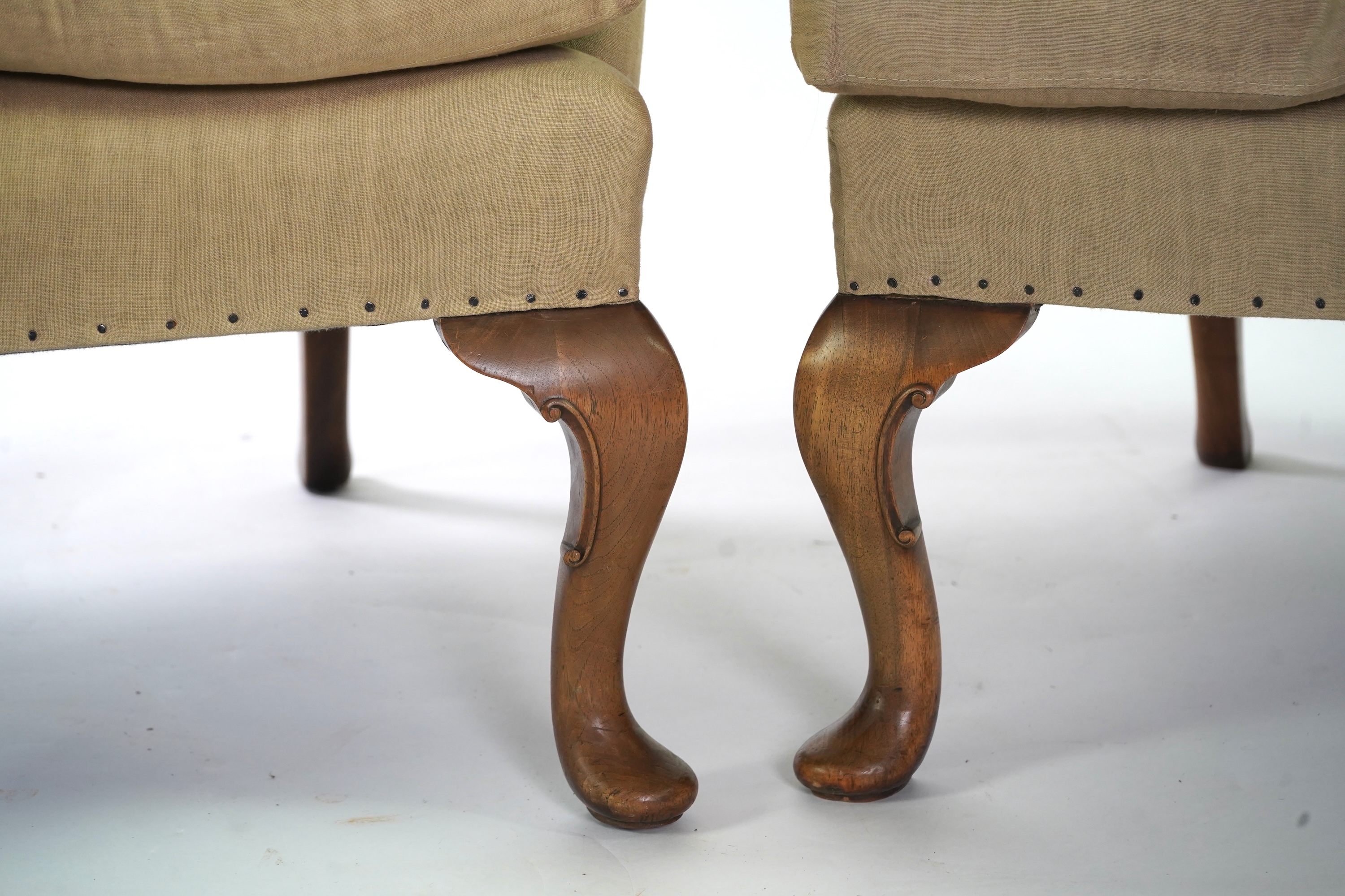 A pair of late 19th / early 20th century George II style upholstered wing armchairs